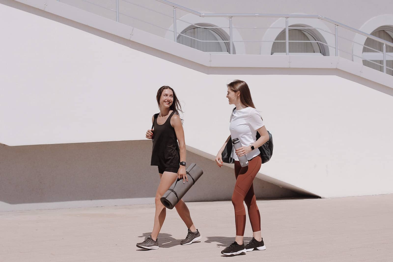 Women Walking Together Carrying Yoga Mat and Black Shoulder Bag