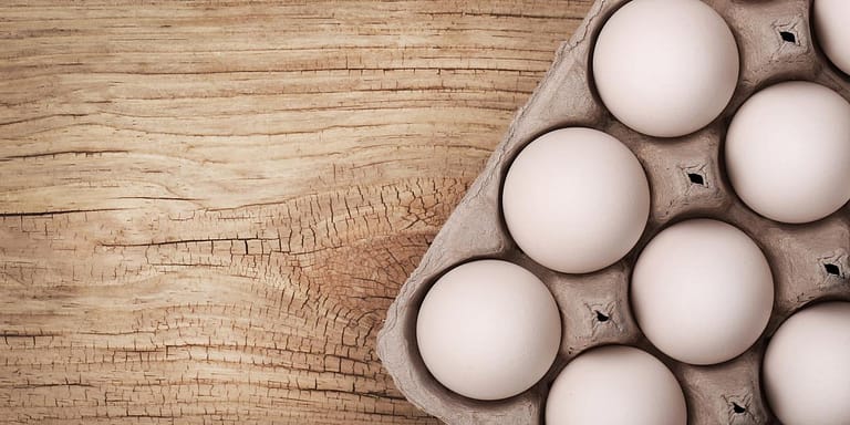 Eggs in carton on wood background